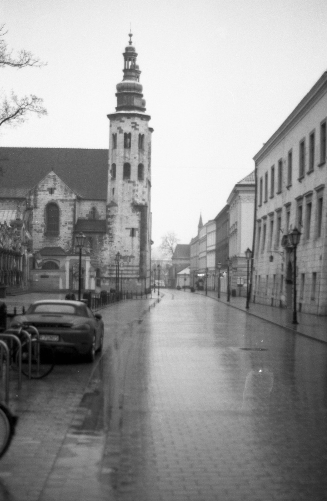 Mokra ulica po deszczu, po lewej romańska wieża kościoła, w oddali kamienice