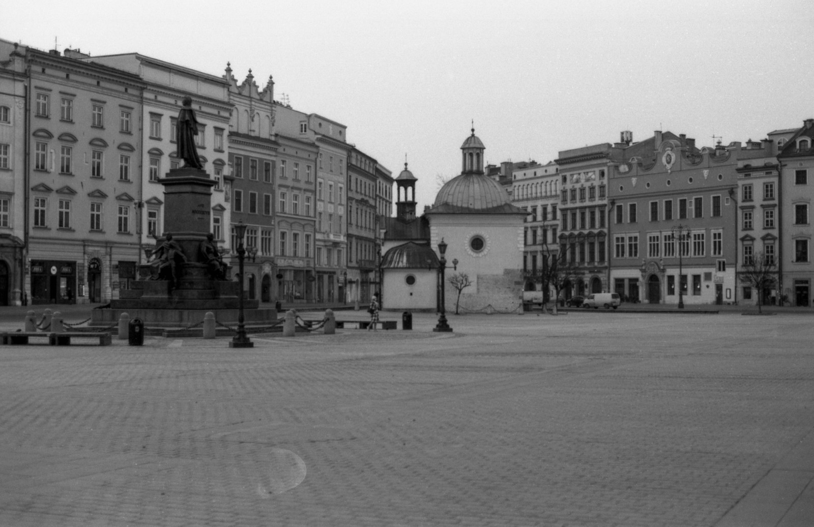 Pusty rynek wyłożony brukiem, pomnik po lewej i mały kościół z kopułą po prawej