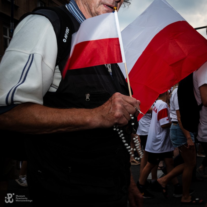 Starszy mężczyzna trzyma małą flagę i różaniec